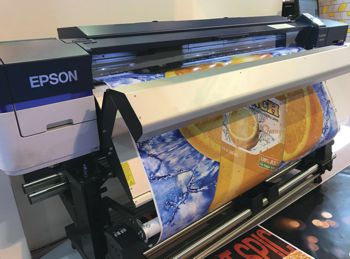 The SureColor SC S60600 printer printing a orange juice bottle