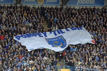 Pompey flag being held by football fans in a crowd at a match.