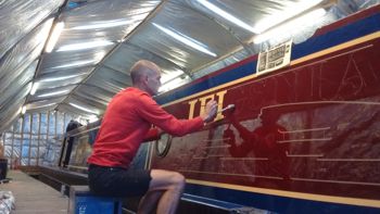 Man signwriting a canal boat by hand