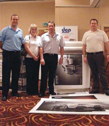 People from DCP Systems and the University Print Service in front of the laminator and some prints.