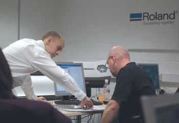 The trainer demonstrating to a peson at a computer at Walsall College.