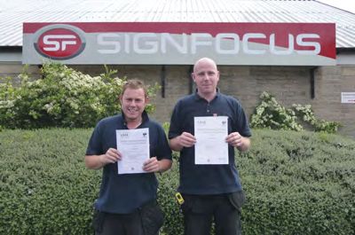 Paul Pratchett and Sam Johnson standing in front of SignFocus premises with their certificate