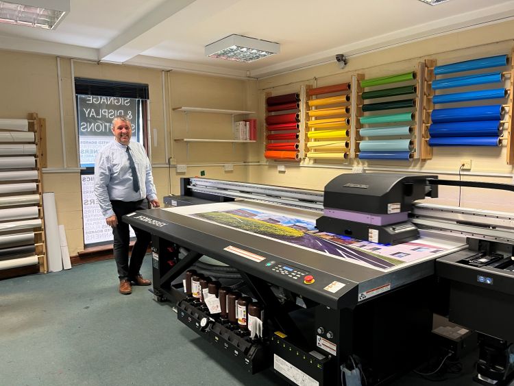 Man standing by new Mimaki flatbed printer
