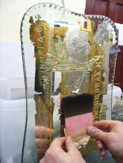 Man working with gold leaf and glass at David’s workshops.