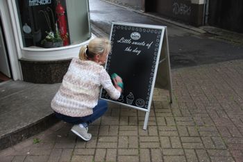 A woman writing on a chalkboard sign