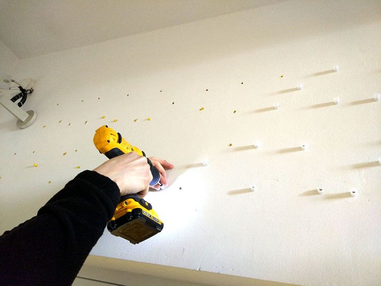 Person drilling holes to place locators into the wall, so flat cut letters can be added after.