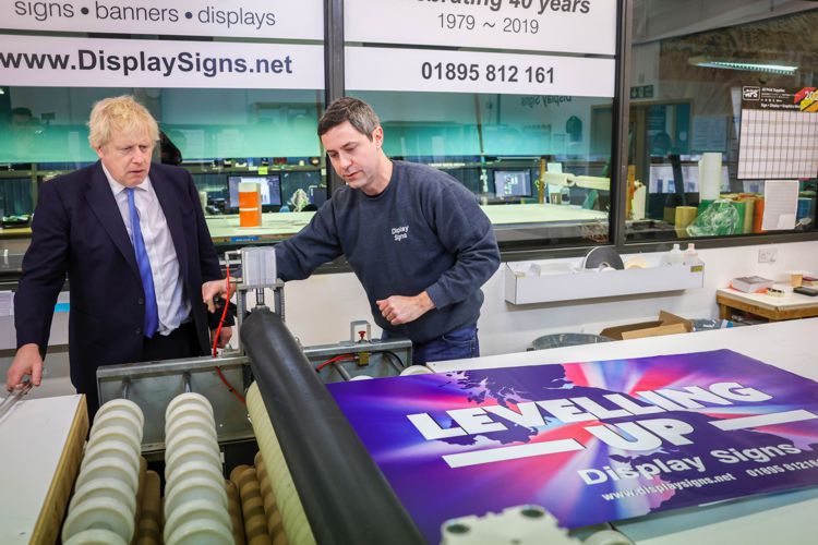 Boris Johnson watching a demonstration of a man using a cold roller 