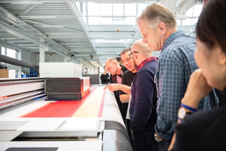 a group of people looking at a flatbed printer