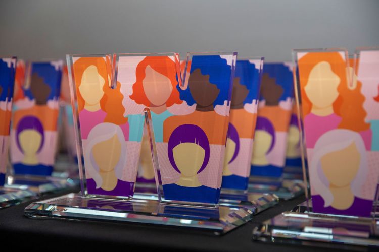 A line of perspex trophies shaped in the letter W with the images of women printed on them 