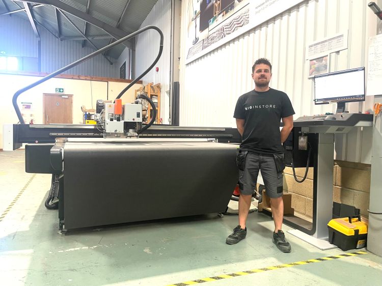 A man stands in a large workshop in front of a new digital cutting table  