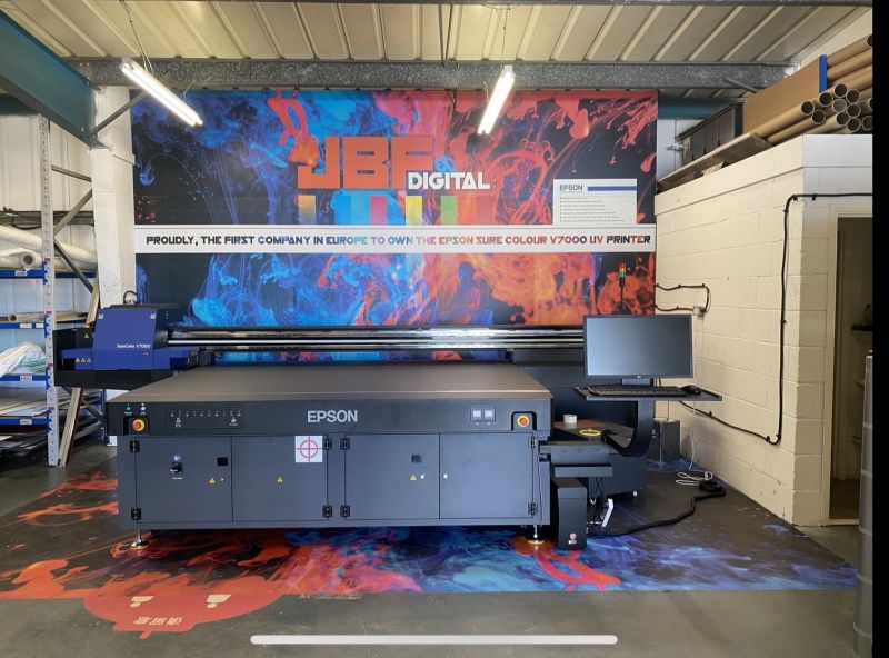 An Epson flatbed printer is placed in the middle of a busy workshop
