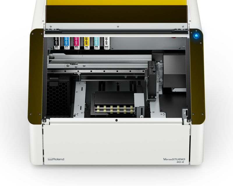 A Roland VersaSTUDIO printer with its cover open against a white background