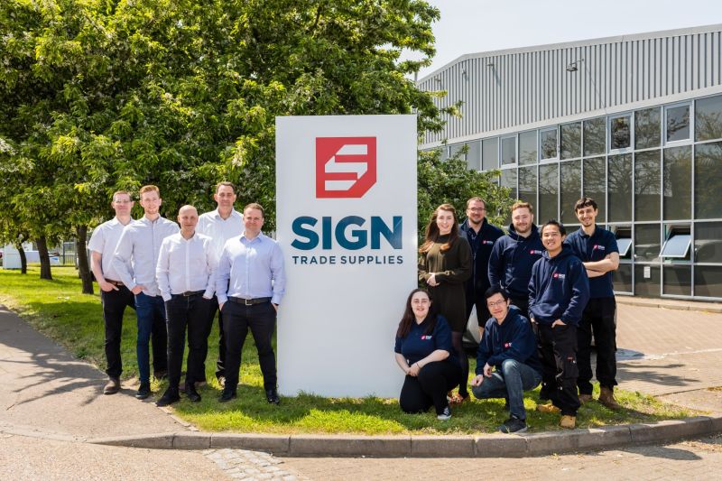 A group photo of the STS team around their company totem sign